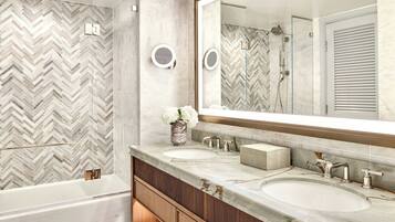 A modern bathroom with a large mirror, two sinks, and a shower.