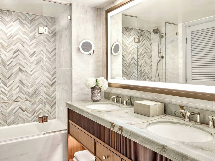 A modern bathroom with a large mirror, two sinks, and a shower.
