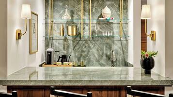 A modern bathroom with a marble backsplash, gold fixtures, and a glass shelf display.