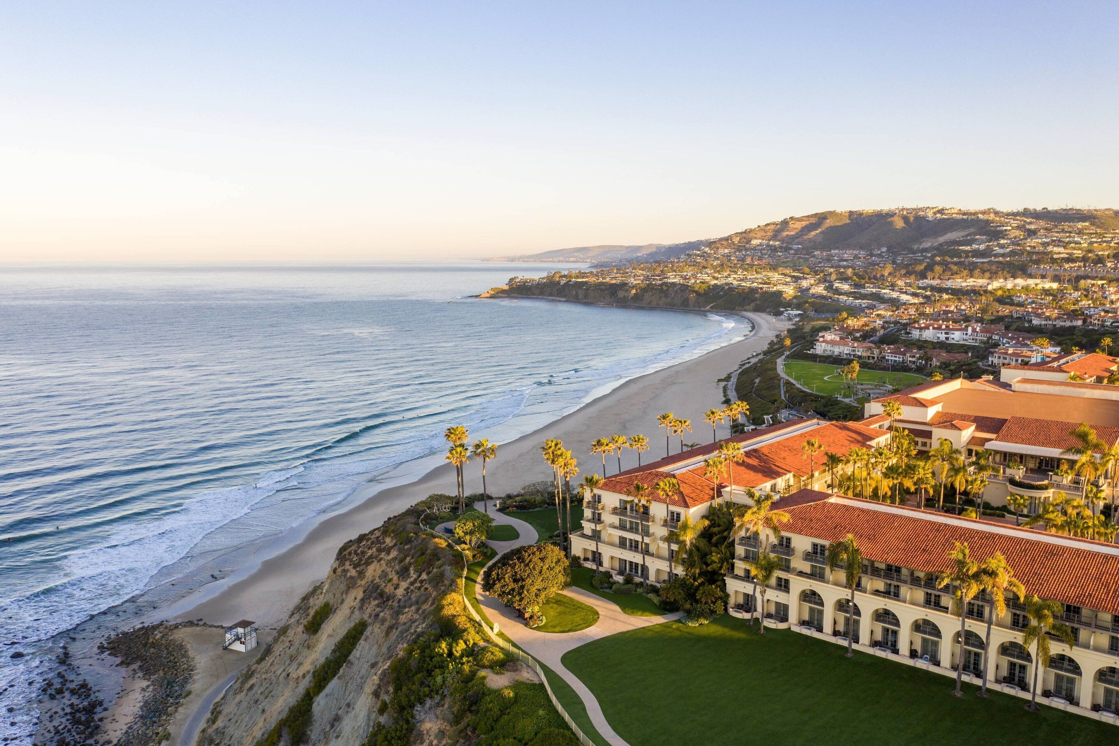 Aerial view of a luxurious beach resort in Southern California, with turquoise waters and white sand stretching into the distance