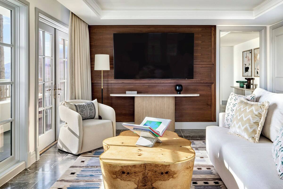 A modern living room with a large flat-screen TV mounted on a wooden wall, a white sofa, a round coffee table, and a floor lamp.