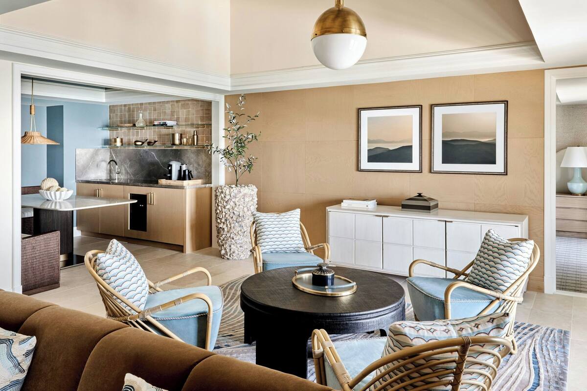 A modern kitchen with a marble countertop, a dining area with wicker chairs, and a large round table.