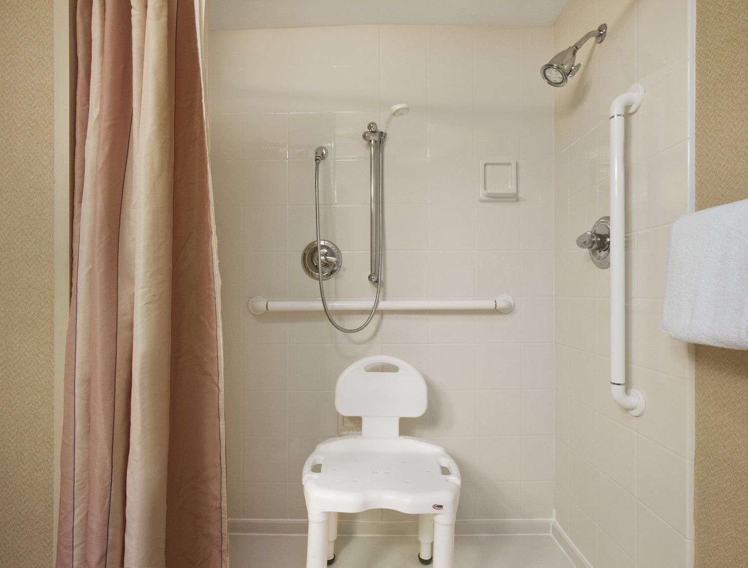 A bathroom with a walk-in shower, grab bar, and a white toilet.