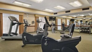 Een hotel fitnessruimte met loopbanden, elliptische trainers en een gewichtrek.