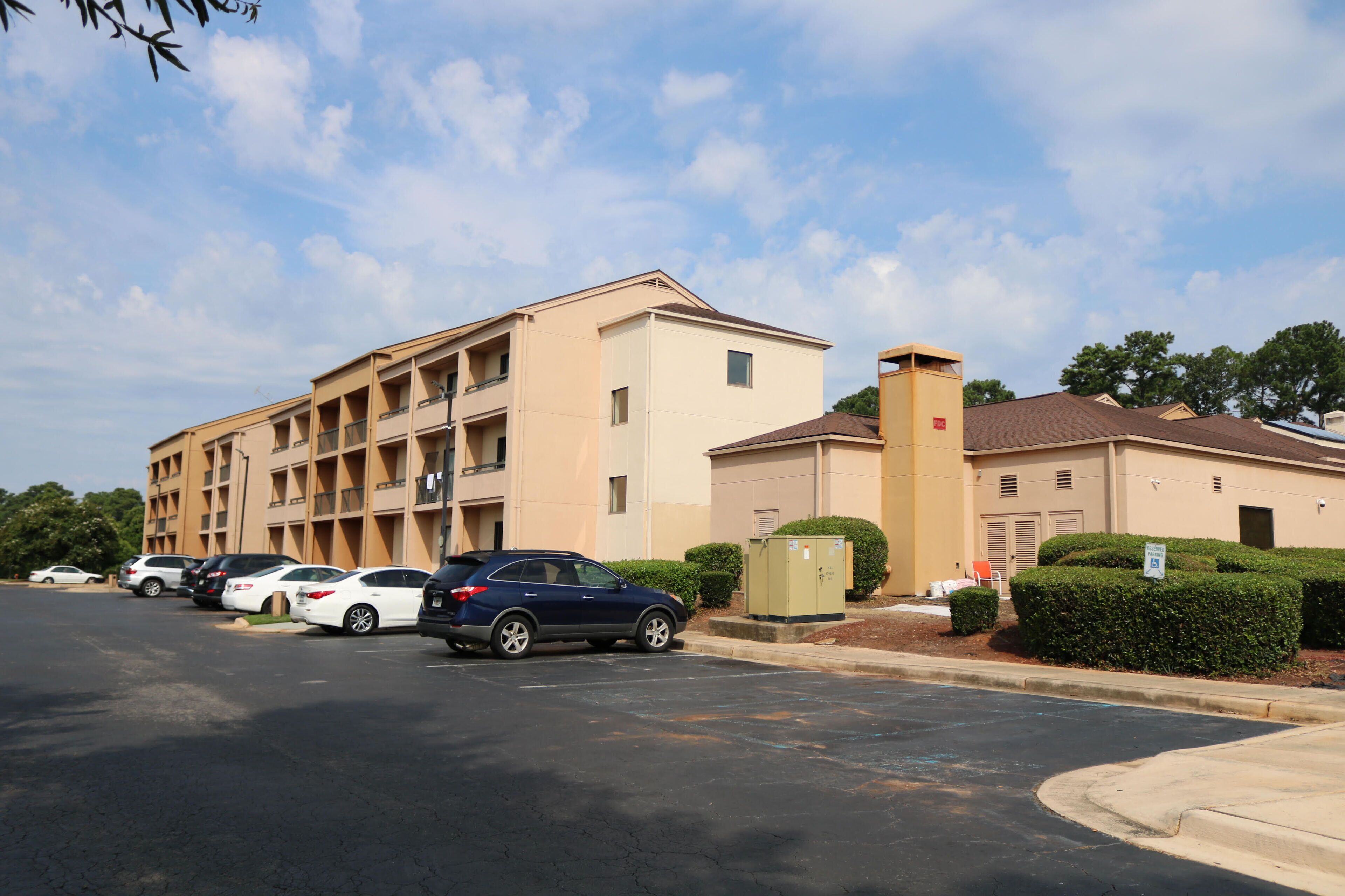 A multi-story building with a parking lot in front.