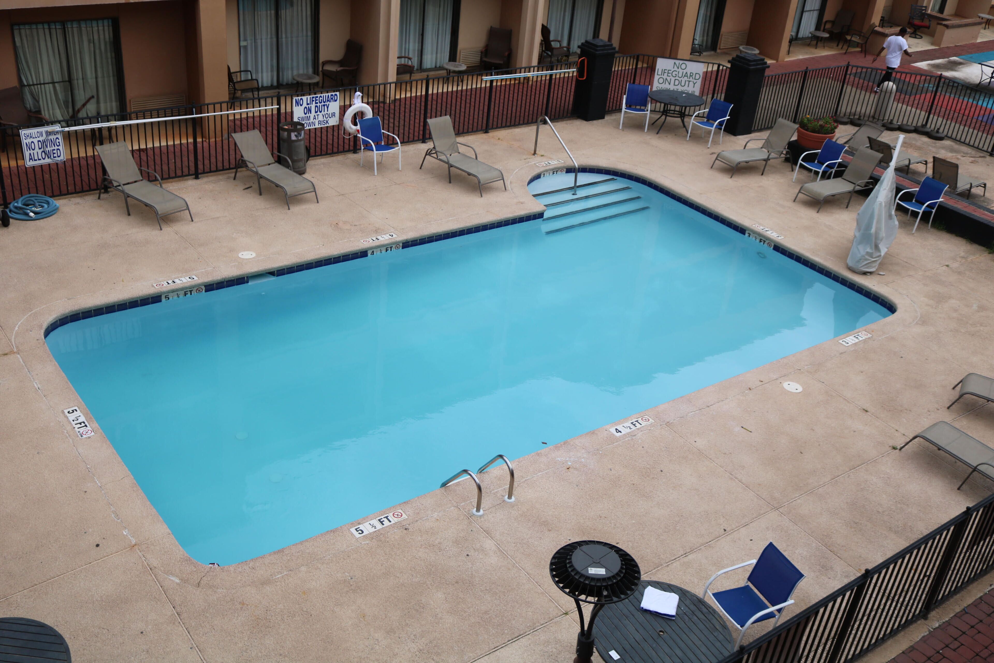 A rectangular pool with a lifeguard stand and lounge chairs around it.