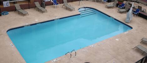 A rectangular pool with a lifeguard stand and lounge chairs around it.