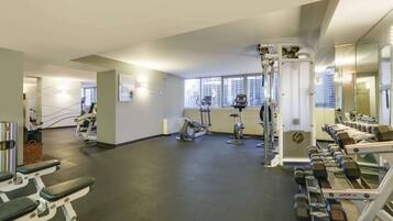 Ein Fitnessstudio mit verschiedenen Trainingsgeräten, darunter Laufbänder, Ergometer und Kraftgeräte.