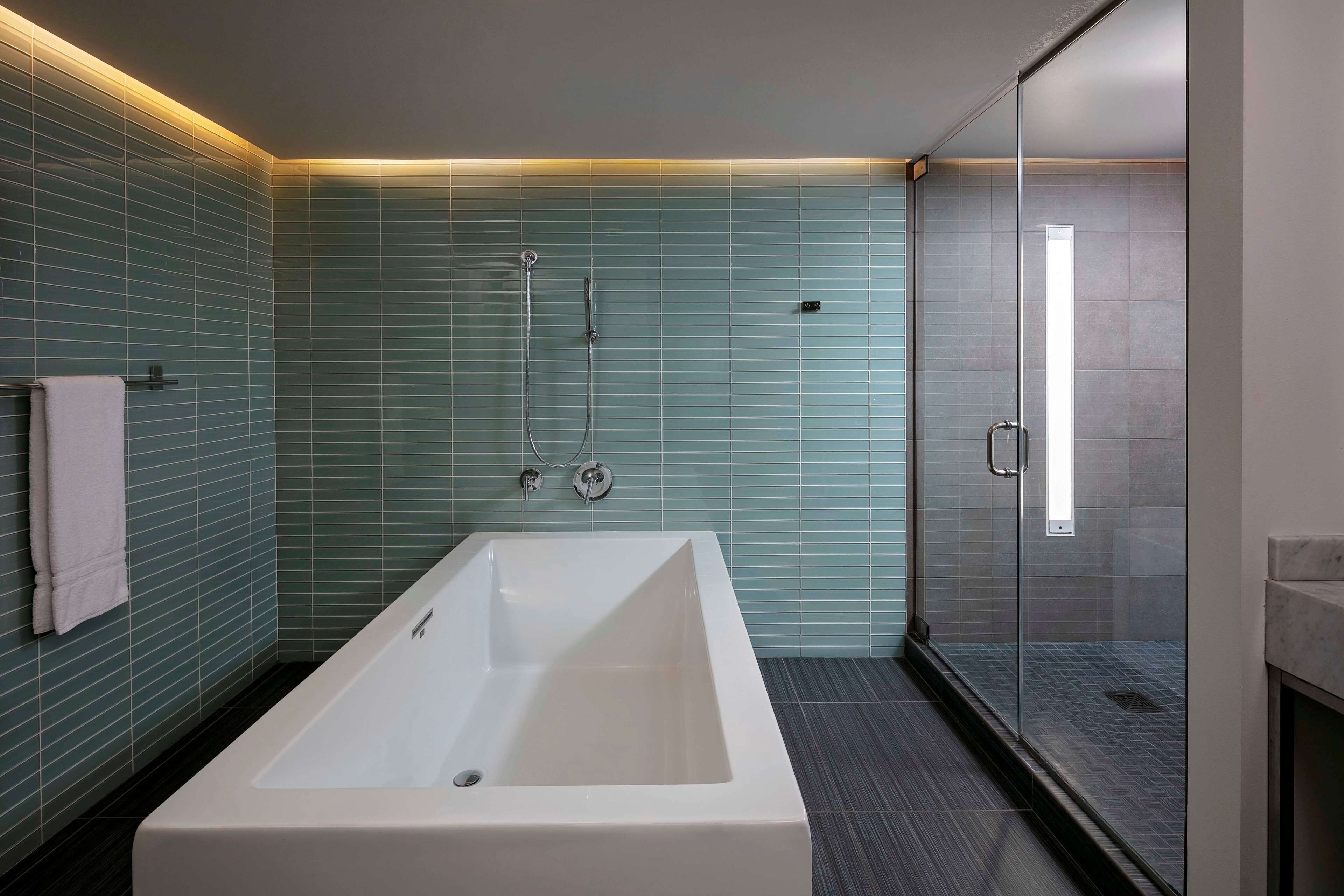 A modern bathroom with a large bathtub, a glass shower enclosure, and a tiled wall.