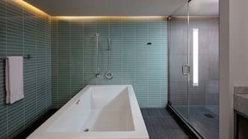 A modern bathroom with a large bathtub, a glass shower enclosure, and a tiled wall.
