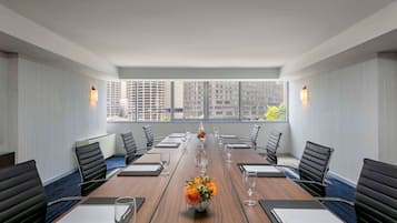 A conference room with a long table, black chairs, and a vase of flowers.