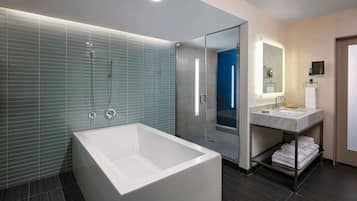 A modern bathroom with a large bathtub, a glass-enclosed shower, and a vanity with a mirror.