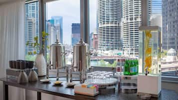 A modern kitchen with a city view, featuring a coffee station, tea pots, and a water dispenser.