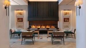 A modern interior with a central fireplace, seating area, and wall-mounted lighting. - The Royal Sonesta Chicago Downtown (Chicago)