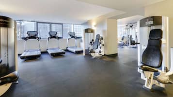 A modern gym with treadmills, weight machines, and a large window.