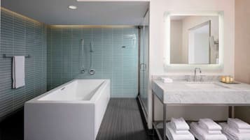 Un baño moderno con una bañera grande, ducha con cerramiento de vidrio y tocador con espejo y lavabo.