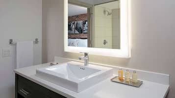 Un baño moderno con un lavamanos blanco, un espejo y un perchero para toallas.