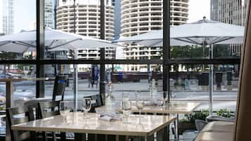 A restaurant with tables and chairs, large windows, and umbrellas.