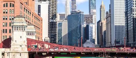A cityscape with a prominent bridge over a green river, surrounded by modern high-rise buildings.