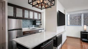 A modern kitchen with a stainless steel refrigerator, a microwave, and a granite countertop.