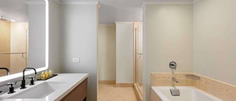 A modern bathroom with a large mirror, a double sink vanity, a bathtub, and a shower area.