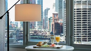 A breakfast table with croissants, a bowl of berries, a glass of orange juice, and a smoothie, set against a cityscape view through a window. - The Royal Sonesta Chicago Downtown (Chicago)