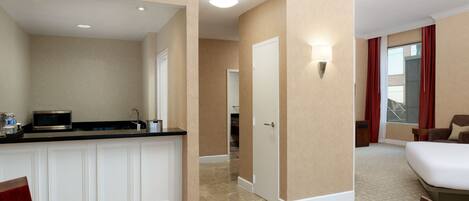 Una habitación de hotel con kitchenette, una cama, zona de estar y baño.