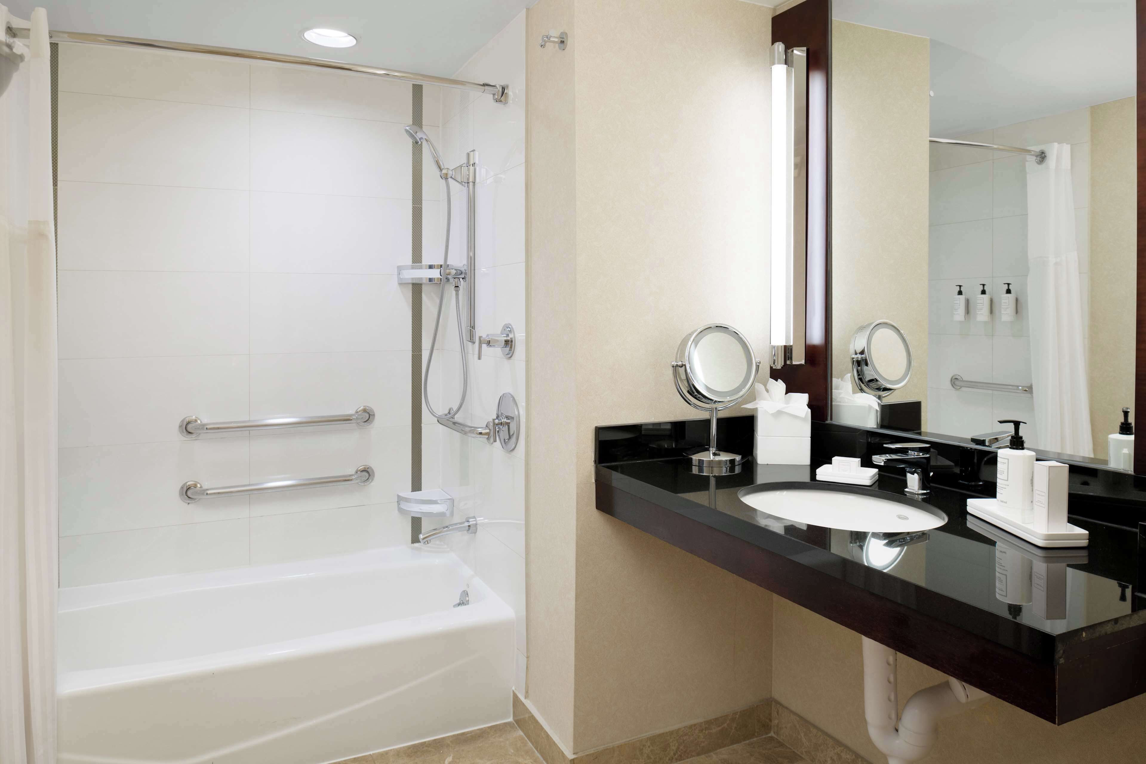 A modern bathroom with a bathtub, a sink, and a vanity mirror.