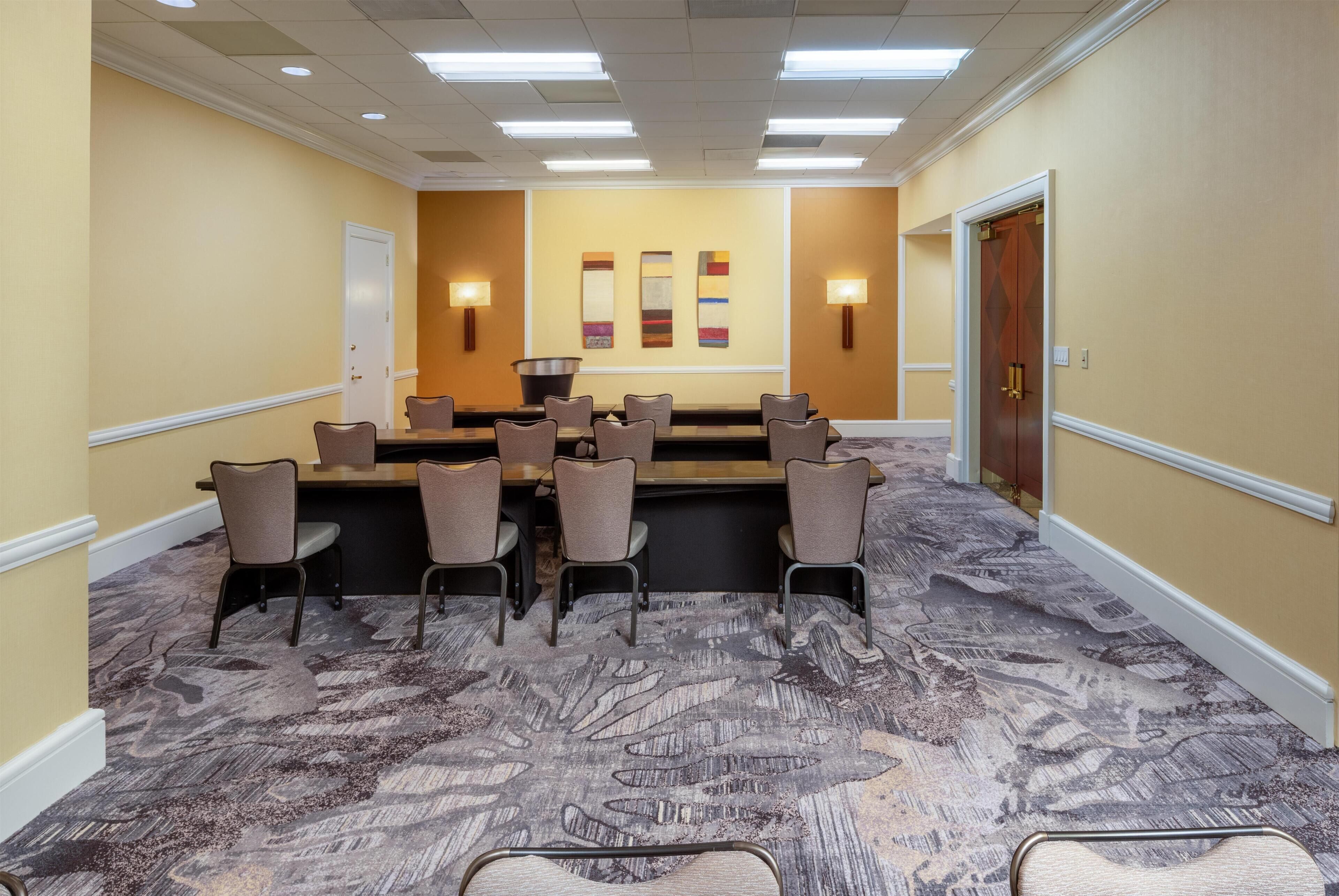 A conference room with a long table, chairs, and a projector screen.