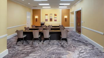 A conference room with a long table, chairs, and a projector screen.