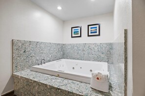 A modern bathroom with a marble countertop, a white bathtub, and two framed pictures on the wall.