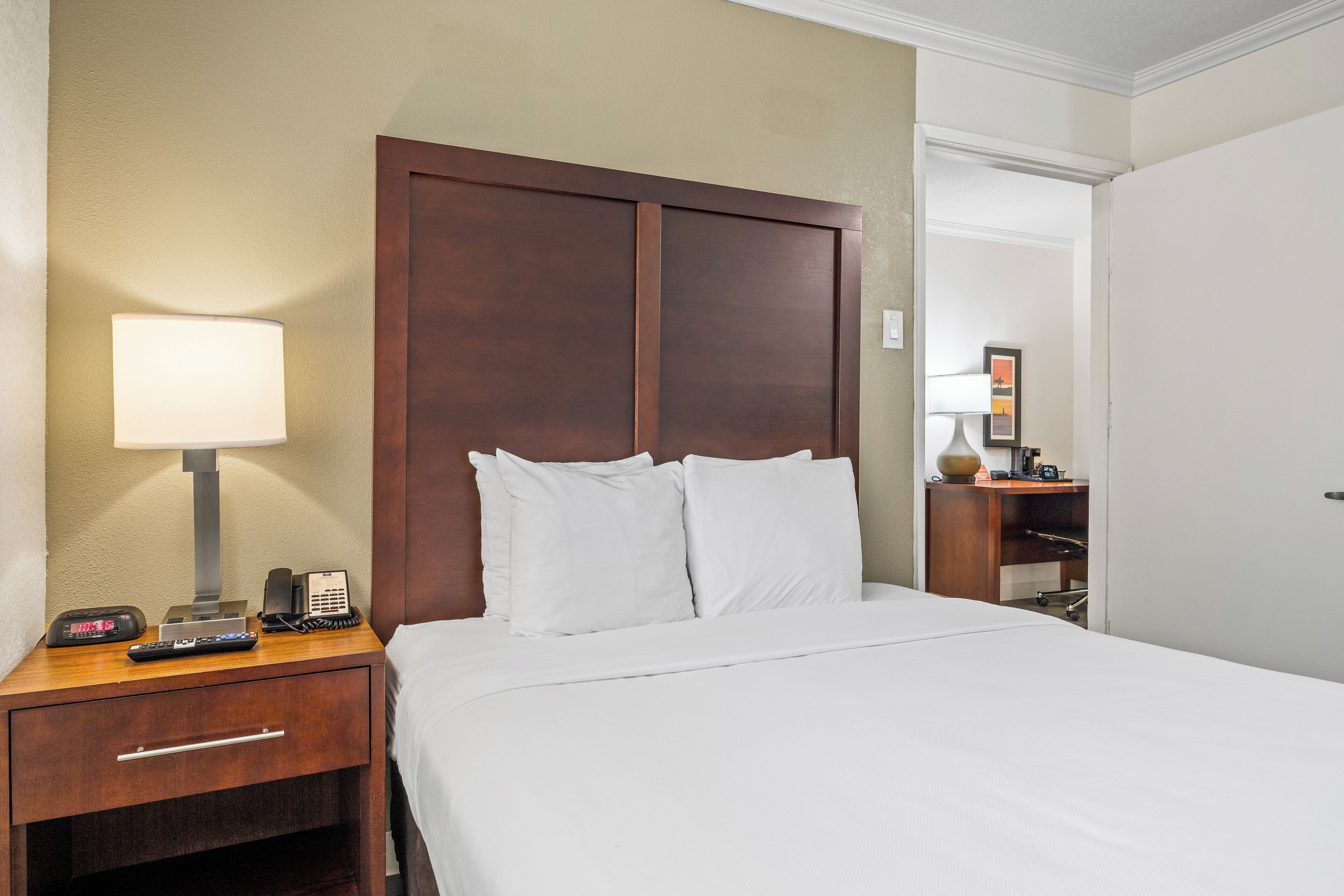 Une chambre d’hôtel avec un lit, une table de chevet avec une lampe, un téléphone et une télécommande.