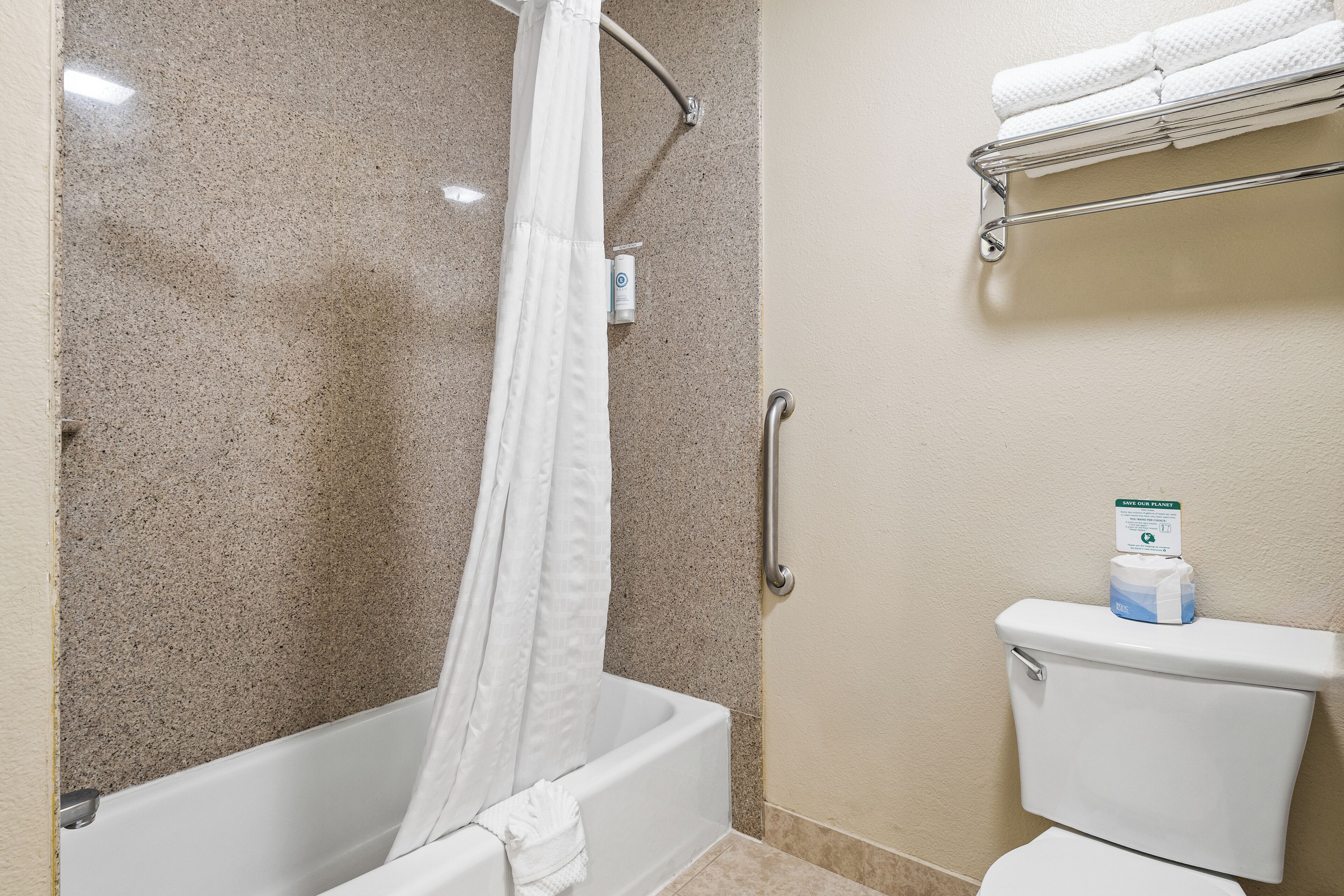 A bathroom with a bathtub, shower curtain, toilet, and a towel rack.