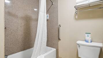 A bathroom with a bathtub, shower curtain, toilet, and a towel rack.