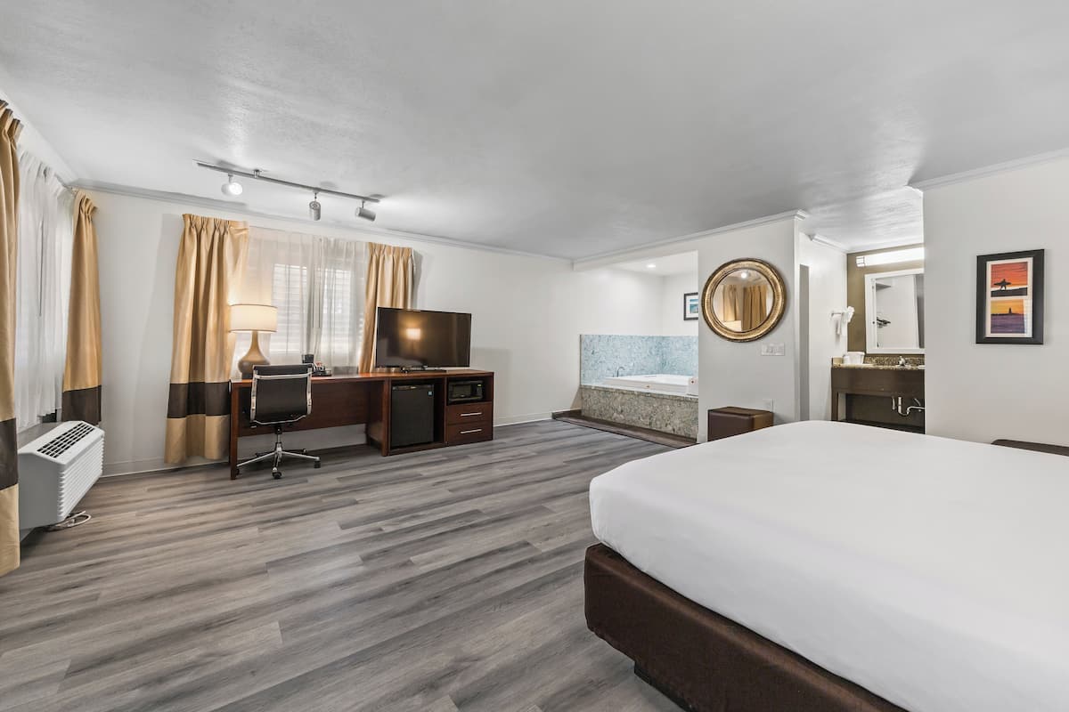 Ein Hotelzimmer mit Bett, Schreibtisch, Fernseher und Badezimmer.