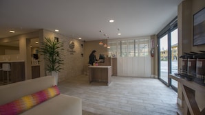 A reception area with a receptionist desk, a large potted plant, a sofa with a colorful cushion, and a view through the glass doors. - Comfort Inn Santa Cruz North (Santa Cruz)