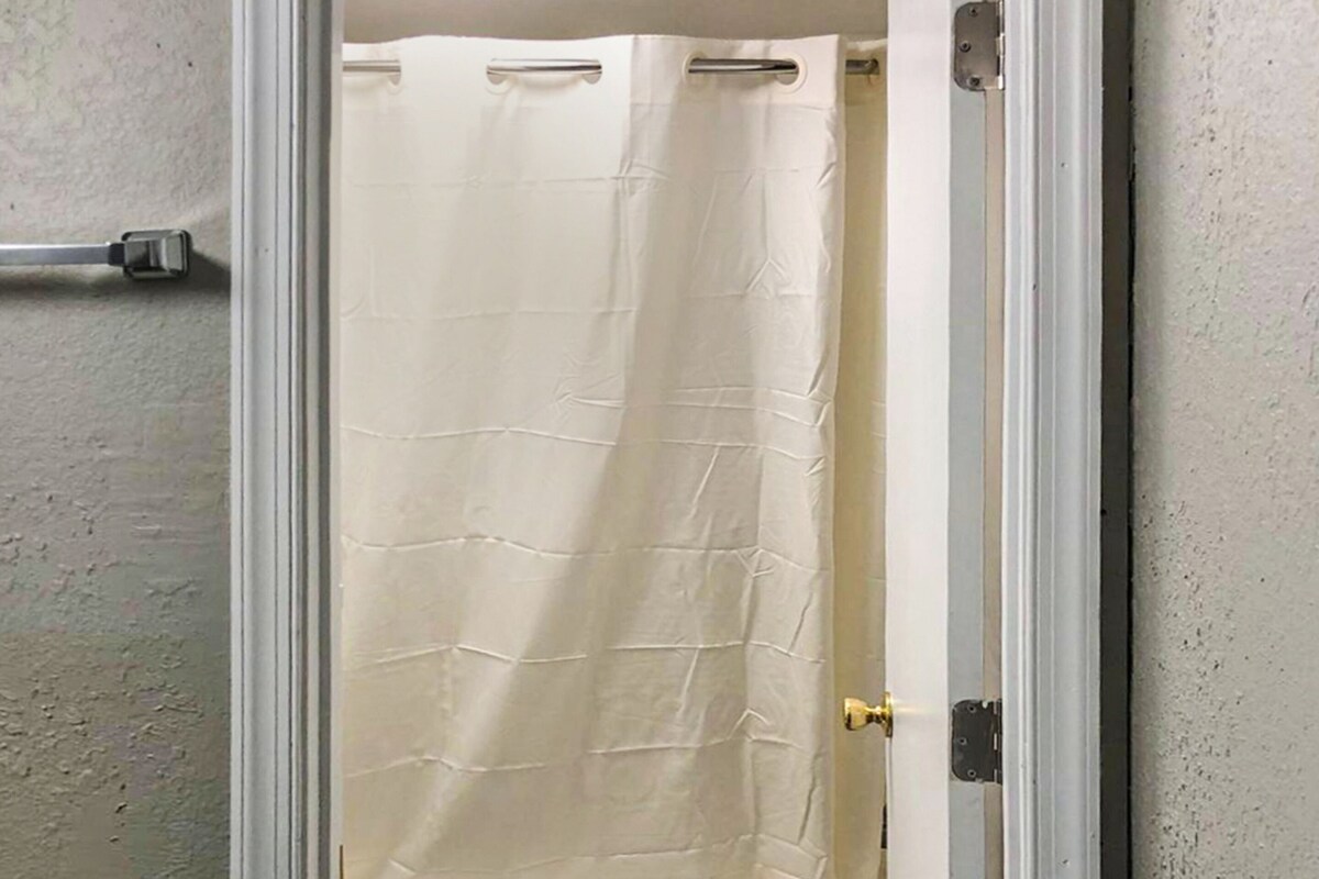 A bathroom with a toilet, a bathtub, and a shower curtain.