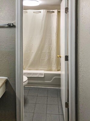 A bathroom with a toilet, a bathtub, and a shower curtain. - OYO Hotel Petersburg VA I-95 & E Washington St (Petersburg)
