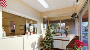 A hotel reception area with a Christmas tree, a small potted plant, and an American flag. - OYO Hotel Petersburg VA I-95 & E Washington St (Petersburg)