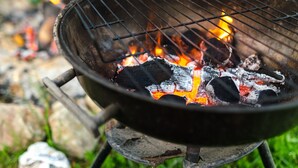 A close-up of a grill with burning charcoal and flames.