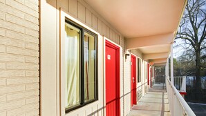 A corridor with red doors and a brick facade.
