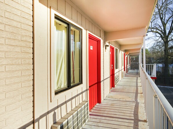 A corridor with red doors and a brick facade. - OYO Hotel Petersburg VA I-95 & E Washington St (Petersburg)