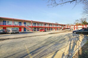 A motel with multiple floors, a parking lot, and a red car parked in front. - OYO Hotel Petersburg VA I-95 & E Washington St (Petersburg)