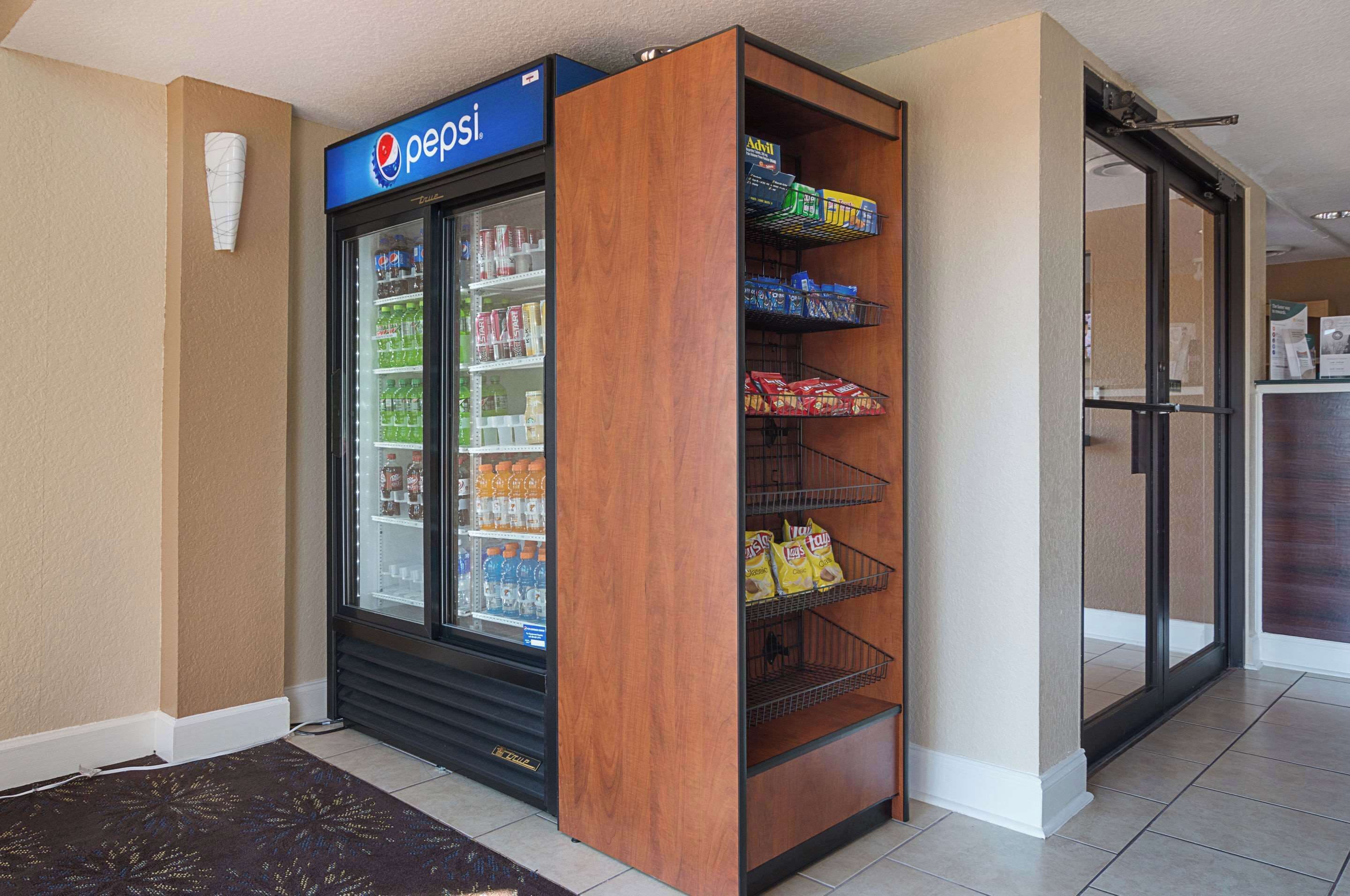 A Pepsi refrigerator with a wooden panel, stocked with beverages and snacks.