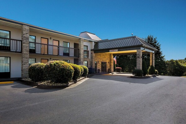 A hotel with a covered entrance, multiple balconies, and a flag outside.