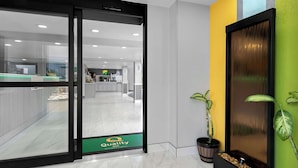 Eine Hotelhalle mit Glastür, einer Rezeption und einer Pflanze in einem Blumentopf.