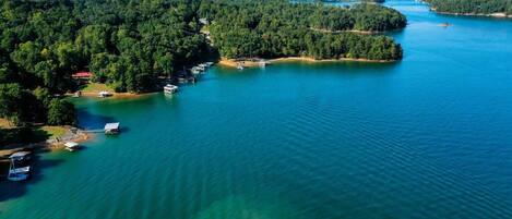 Vista aérea de un lago rodeado de bosques densos y varias embarcaciones amarradas a la orilla.