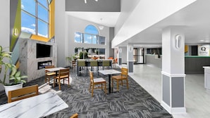 Eine moderne Hotelhalle mit Essbereich, großen Fenstern und einer Rezeption.