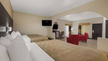 Quarto de hotel com duas camas, uma mesa, uma televisão e uma cadeira vermelha.