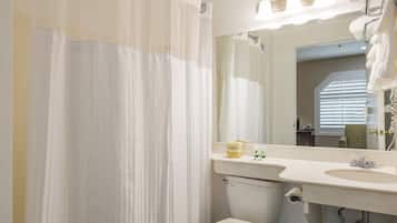 Un baño con inodoro, lavamanos y cortina de ducha.